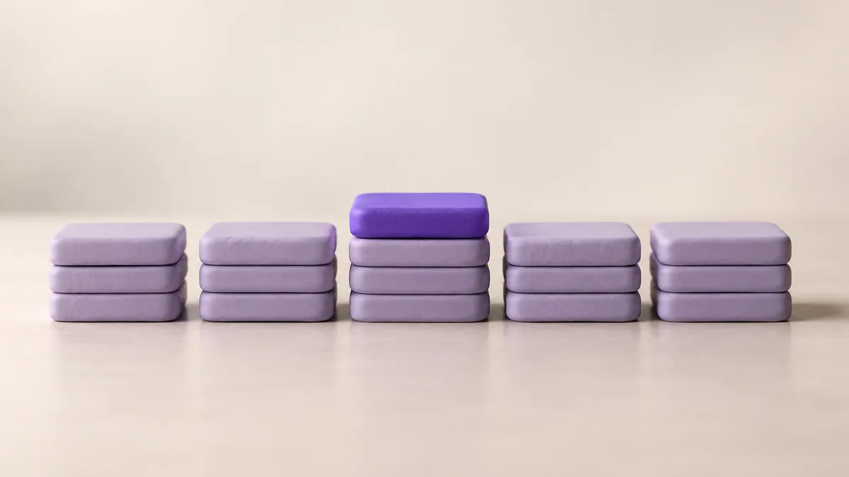 Five low stacks of lavender clay tiles in a row, the middle stack topped by one violet tile placed back on top