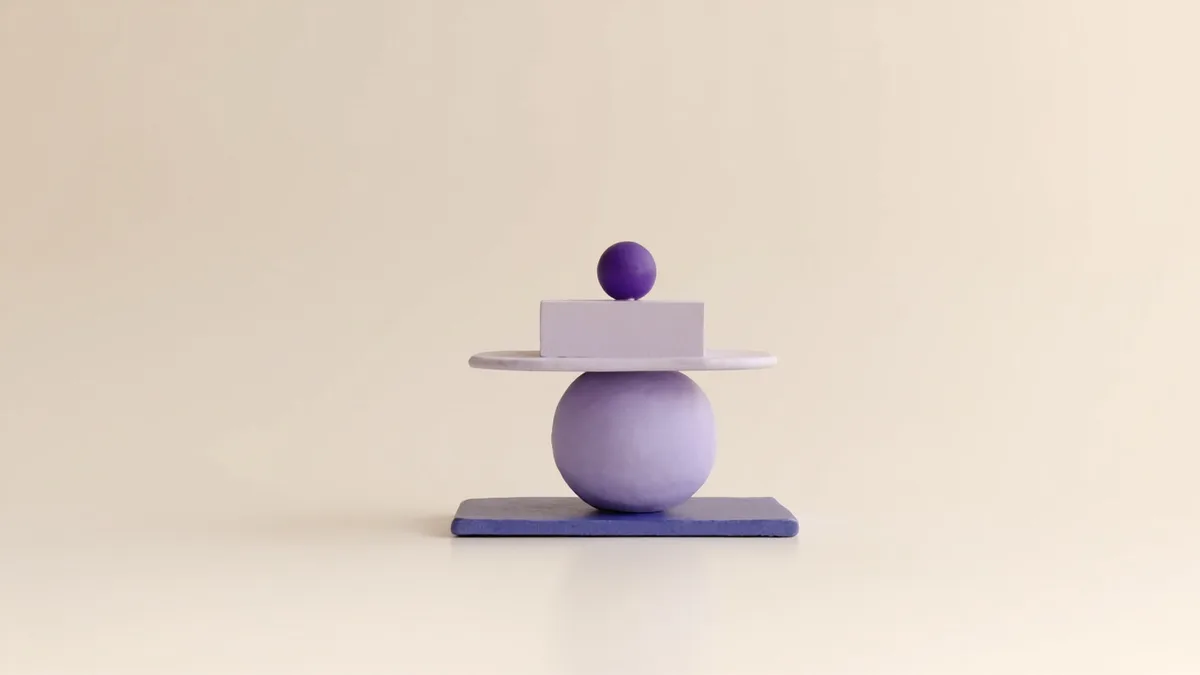 A small balanced stack of clay shapes — a flat base, a round body, a block, and one small sphere at the peak — value first, one offer on top